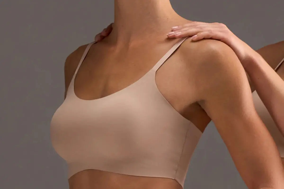 Support bralette in a nude tone with seamless design and thin straps modeled against a neutral background.