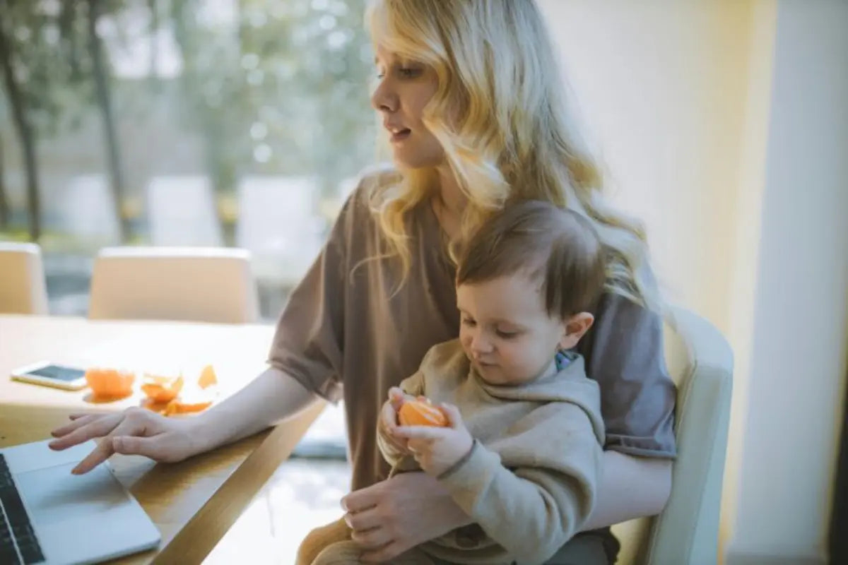 Supportive bralettes worn by a mom working on a laptop while holding her toddler during a cozy daytime moment.