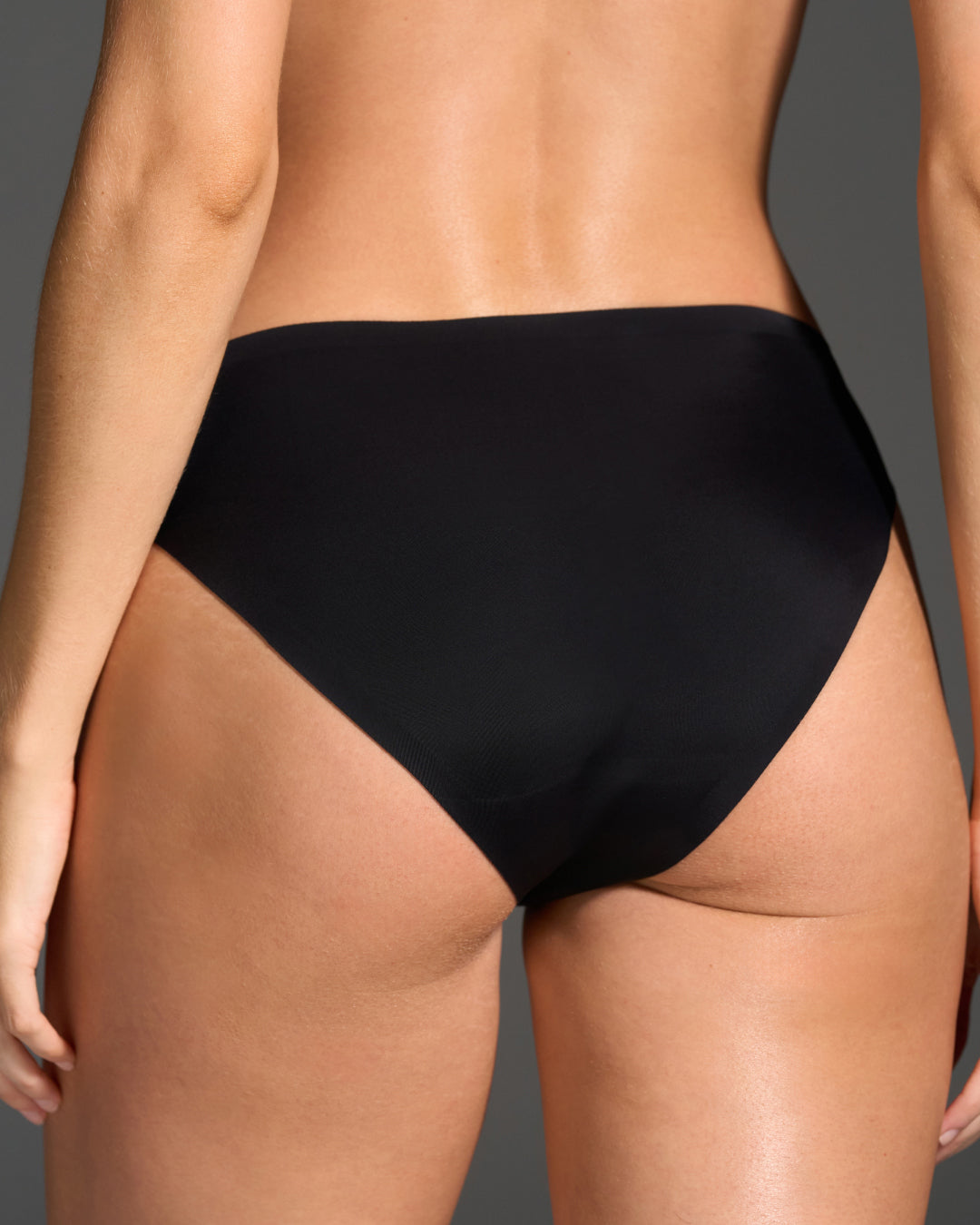 Back view of EBY black seamless bikini panties showing high-cut leg and smooth coverage.