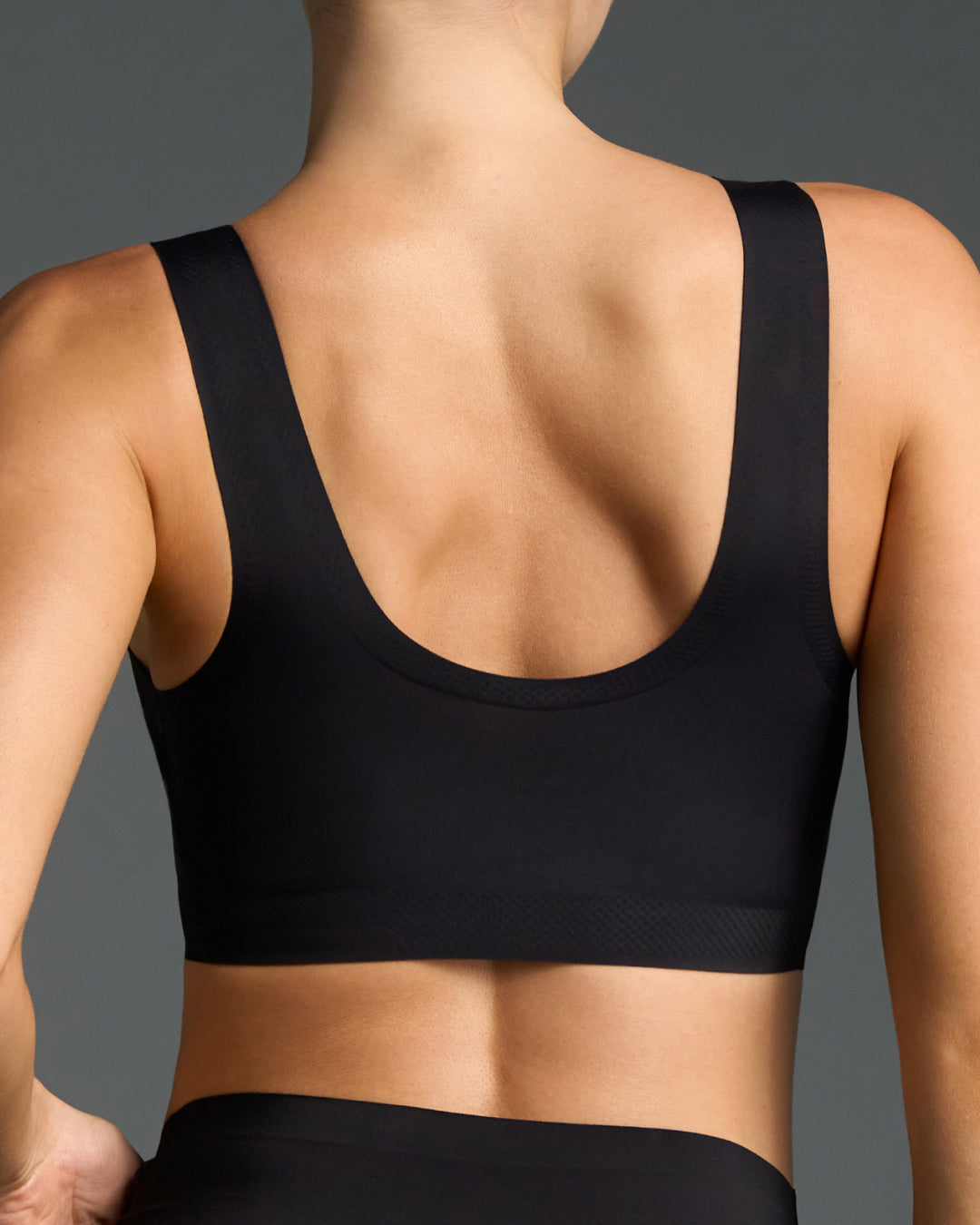 Back view of model wearing black wireless bralette and bikini panties set.