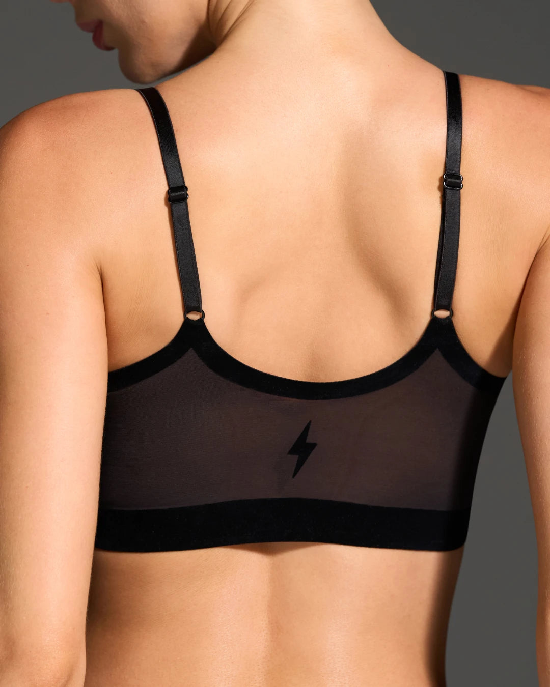 Back view of black sheer mesh wireless bralette with adjustable straps and lightning bolt detail.