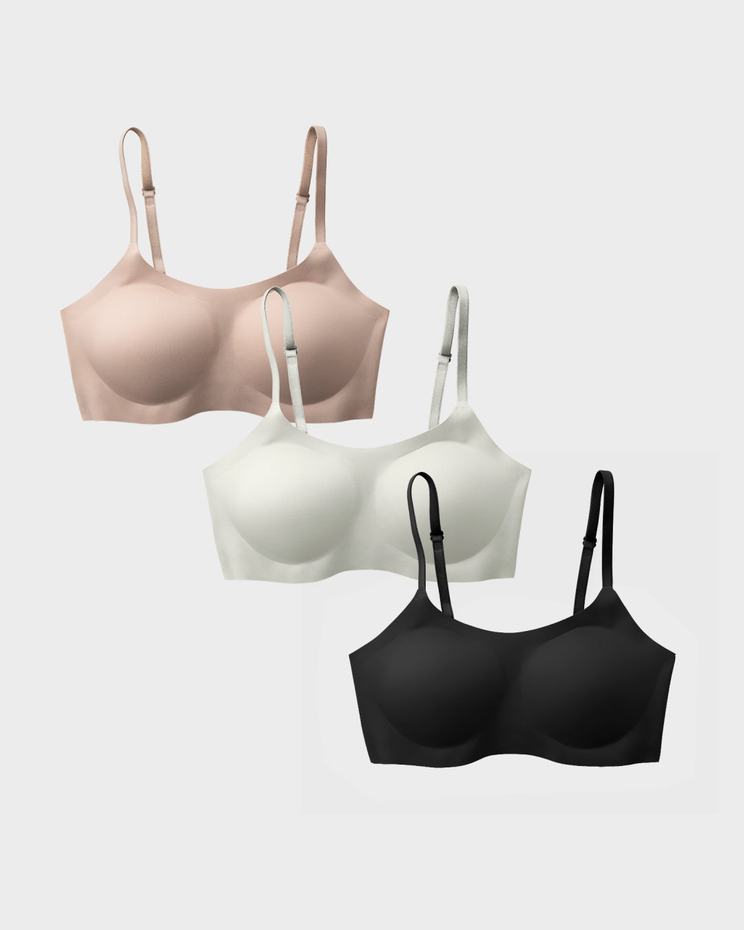 Three support bralettes in black, nude, and pearl in a cascading flat-lay arrangement.
