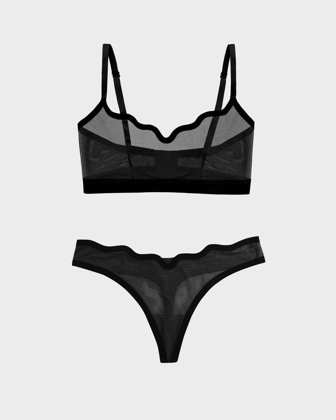 Sheer black mesh wireless Lucy bra with scalloped trim and matching sheer thong, flat-lay.