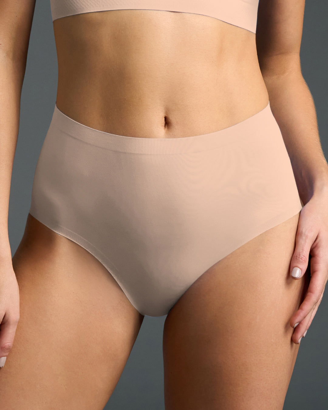 Beige high rise seamless panties shown on model, featuring a smooth stretch fabric with laser-cut edges for invisible comfort and a flattering, full-coverage fit