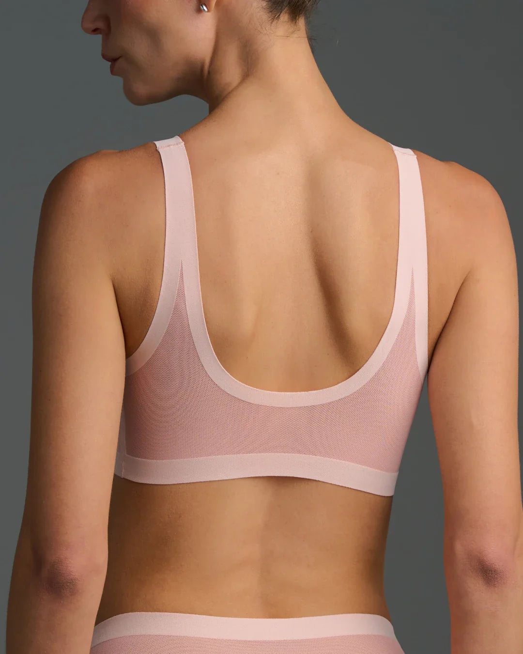 Back view of model wearing murex shell sheer bralette with scoop back and mesh detail.