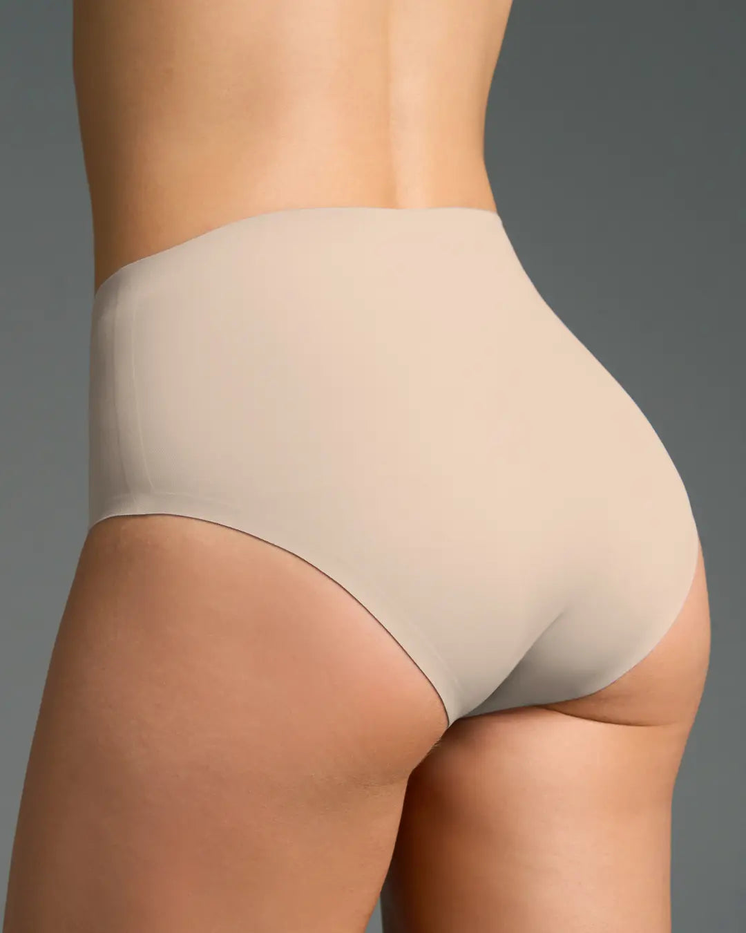 Nude seamless high-waisted panties shown on model from the back, smooth full coverage.