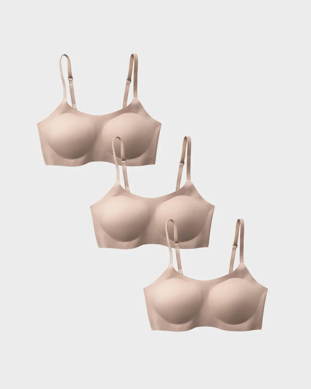Three nude support bralettes in a cascading flat-lay arrangement.