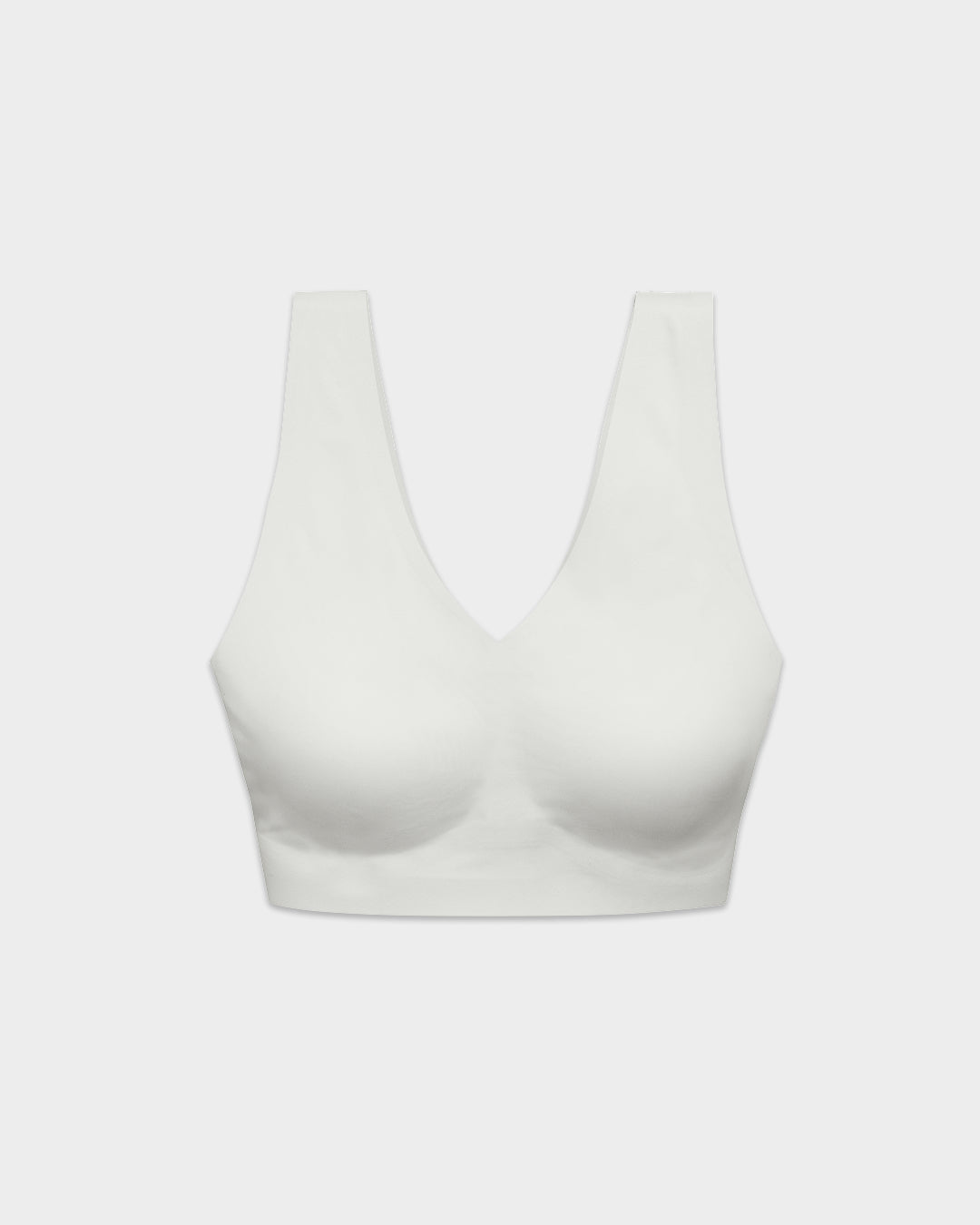 White seamless wireless Pearl bralette with V-neckline and wide straps on grey backdrop.