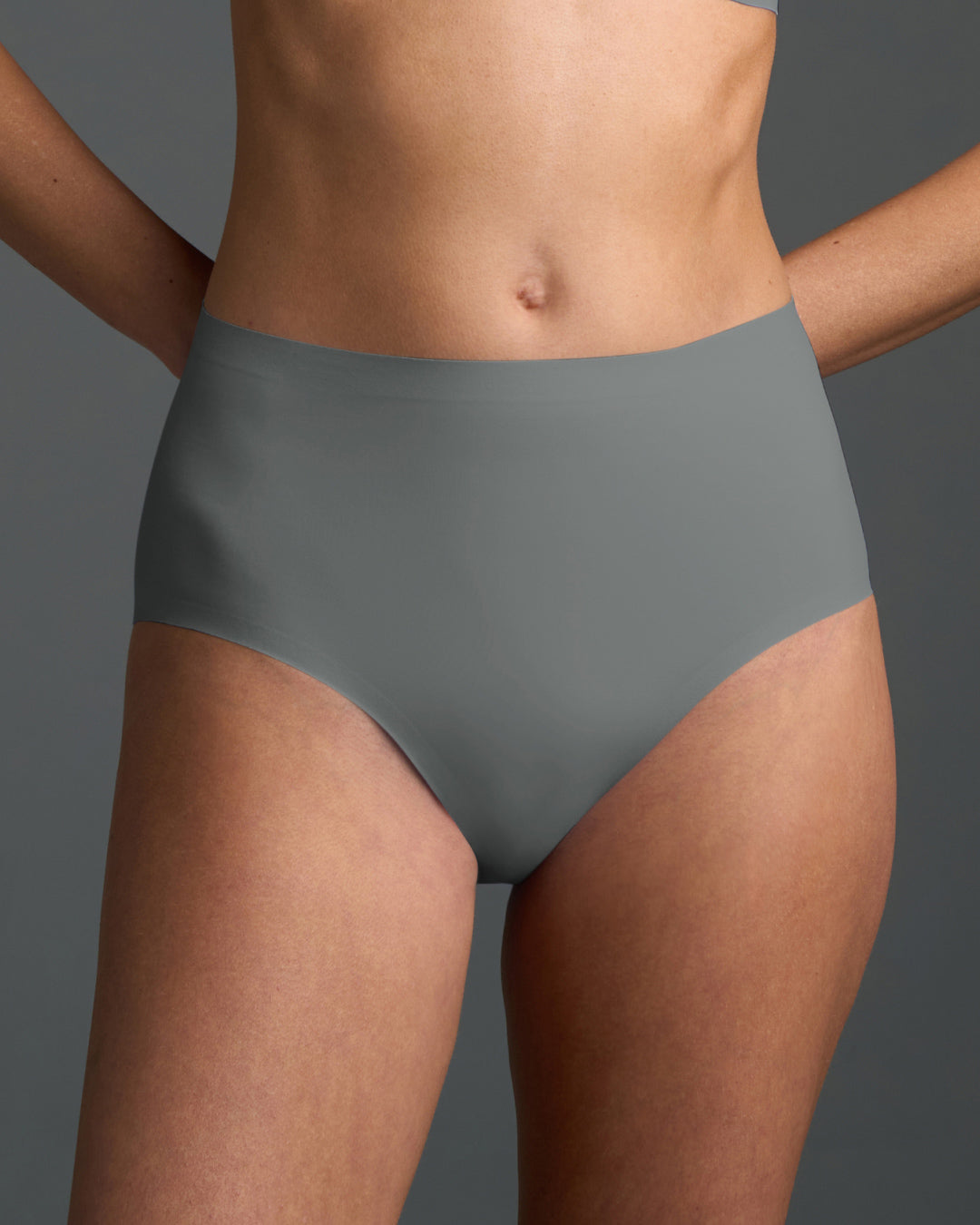 Gray high rise no show panties shown on model, featuring a smooth, seamless design with stretchy fabric and a high-waisted fit for invisible comfort under clothing
